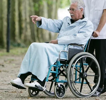 Auxiliaire de vie accompagnant une personne en fauteuil roulant lors d'une promenade