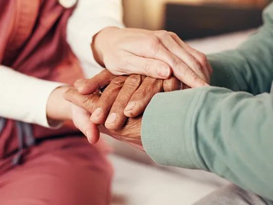 Soignante tenant les mains d'une personne âgée lors d'une assistance de nuit à domicile