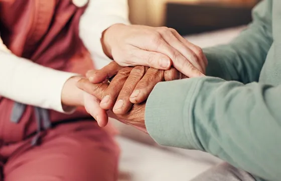 Soignante tenant les mains d'une personne âgée lors d'une assistance de nuit à domicile