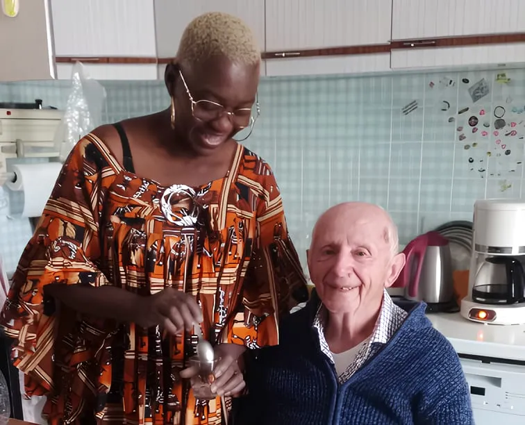 Auxiliaire de vie souriante aux côtés d'un homme âgé dans une cuisine